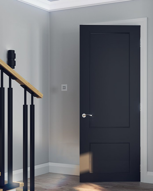 A modern black two-panel door with traditional mouldings, installed in a home environment with visible staircases on the side.